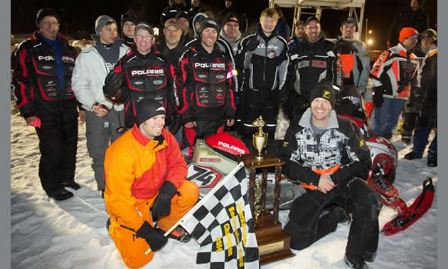 Bunke Racing drivers and crew members gathered around the first-place trophy and winning sled