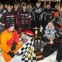 Bunke Racing drivers and crew members gathered around the first-place trophy and winning sled