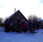 Snowmobiling warm-up shelter with a group of sledders gathered outside it.