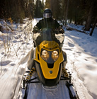 a solo snowmobiler on a forested trail