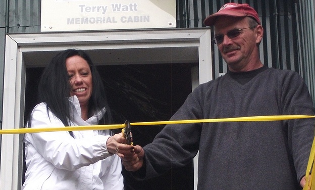 Terry Watt's daughter, Llana Malmberg, along with  JayDee McClure cutting the ribbon of the newly finished Terry Watt memorial cabin.  