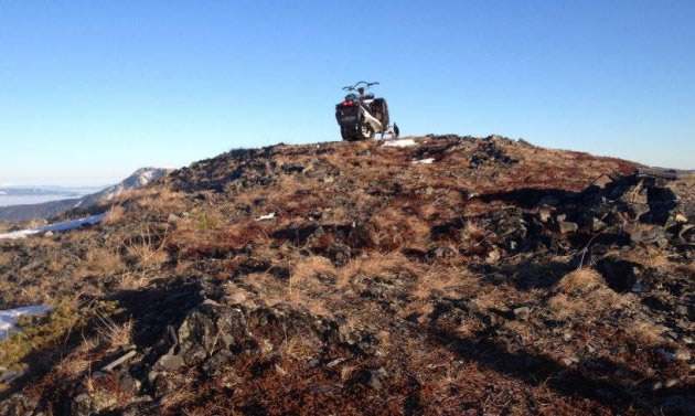 A snowmobile sitting on the top of a bare rock. 