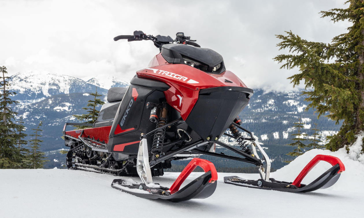 A red Taiga snowmobile parked on a mountain. 