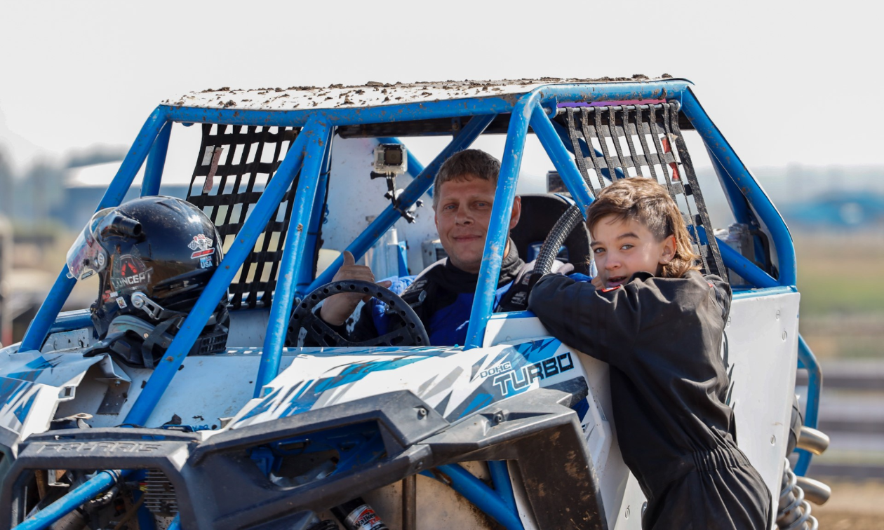 Richard Bernard smiles from within his Polaris RZR ATV while a boy converses with him. 