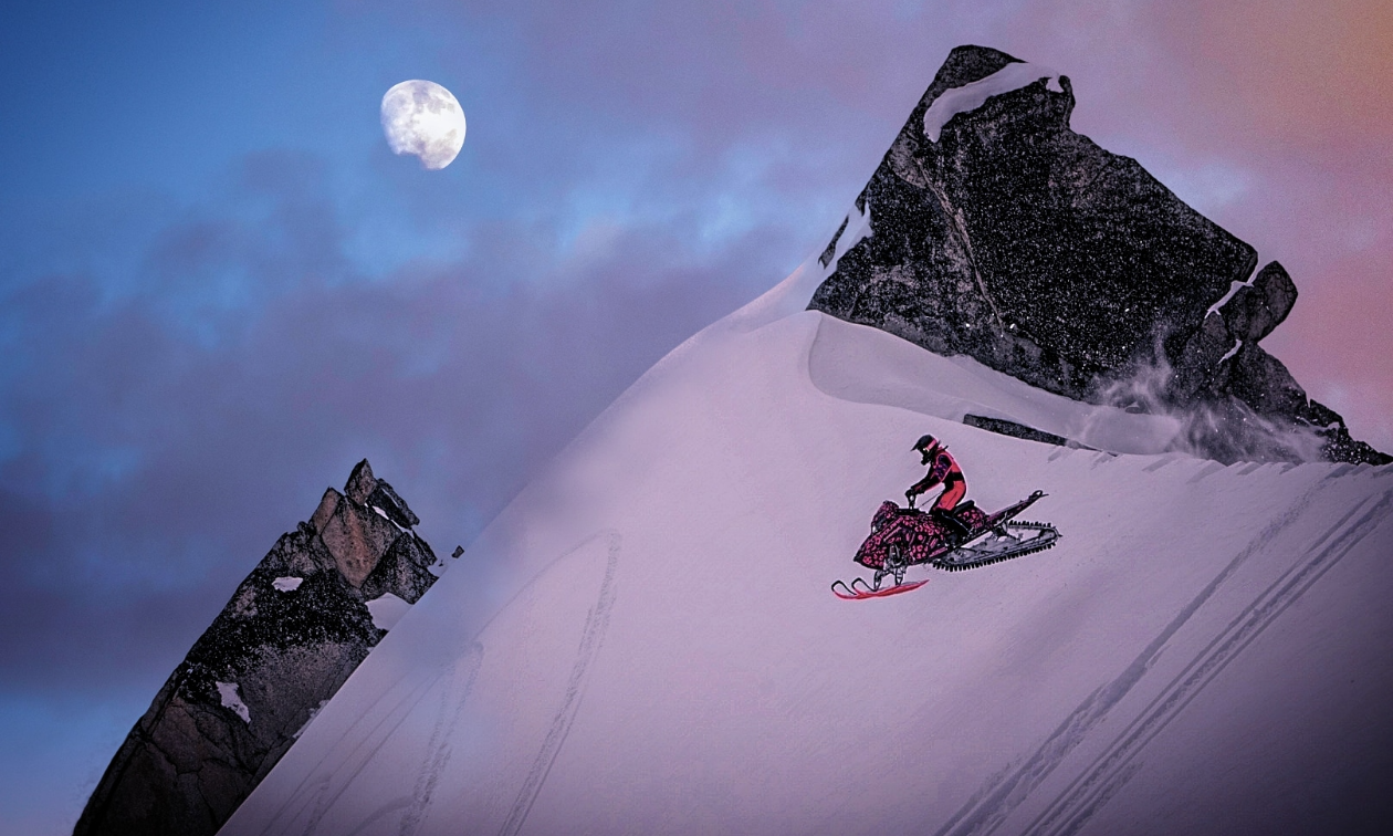 Gabrielle Hockley gets major air over a mountain jump on her snowmobile with the moon peeking out between hazy blue and pink clouds. 