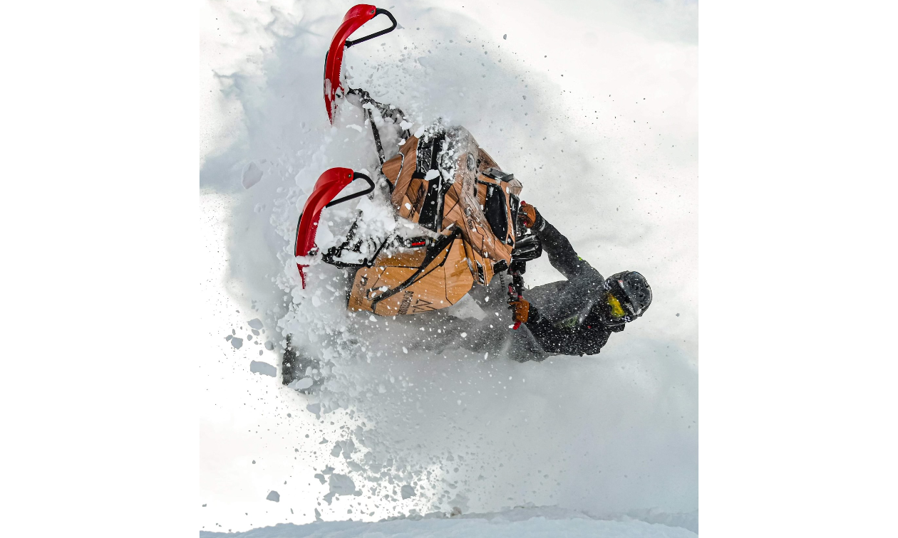 Brandon Milford does a barrel roll with his custom-wrapped snowmobile as white powder poofs around his aerial wake. 