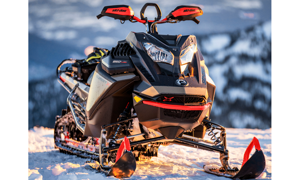 A 2022 Ski-Doo Summit snowmobile on top of a snowy mountain.