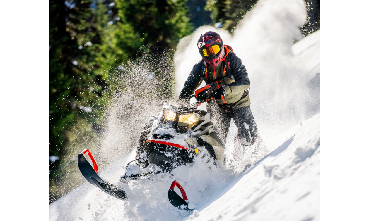 Carl Kuster rides a 2022 Ski-Doo Summit snowmobile on top of a snowy mountain.