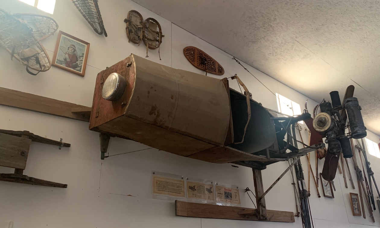 A homebuilt, repurposed, modified old snowmobile hung up on a wall. 