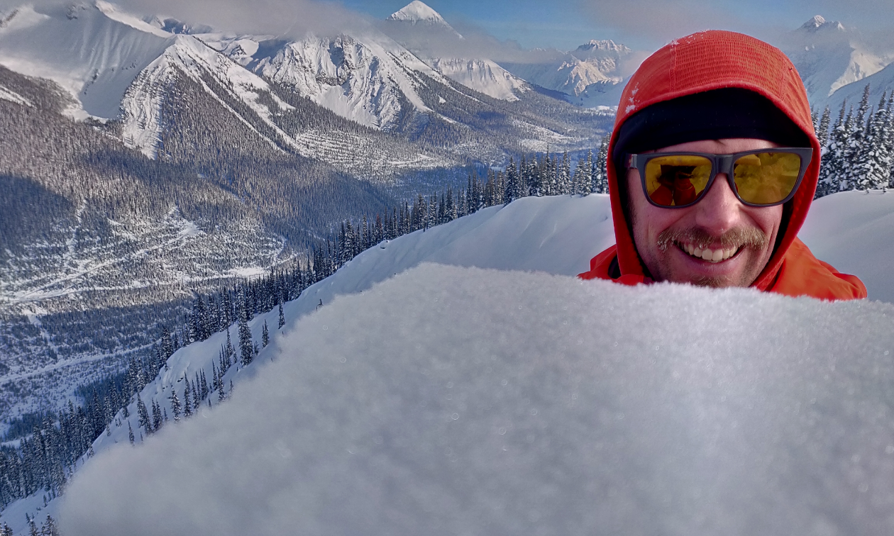 Grant Helgeson smiles while hiding his body behind a pile of snow. 