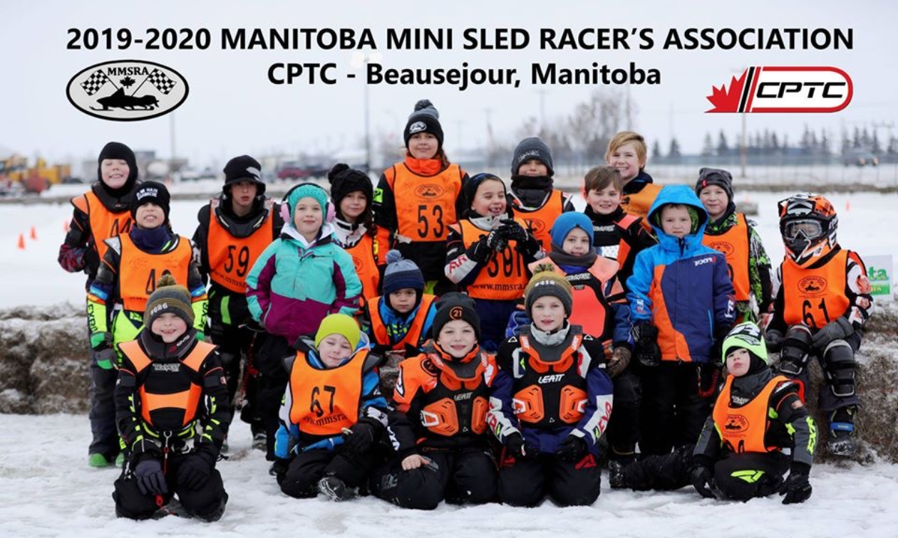 A group of children wearing orange pinnies overtop of winter clothing are part of the 2019-2020 Manitoba Mini-Sled Racer’s Association.