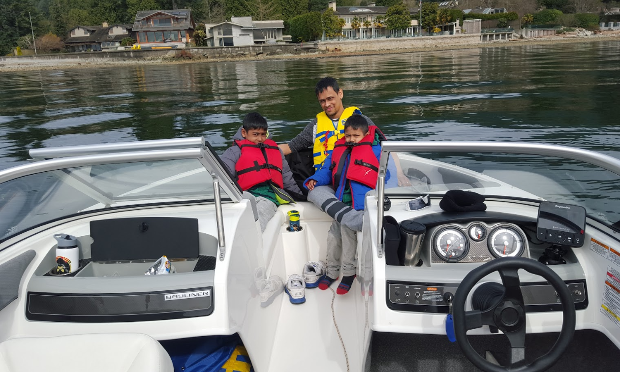 Melvin Garib sits next to two of his sons while wearing life jackets on his 2015 Bayliner 190 OB Bowrider. 