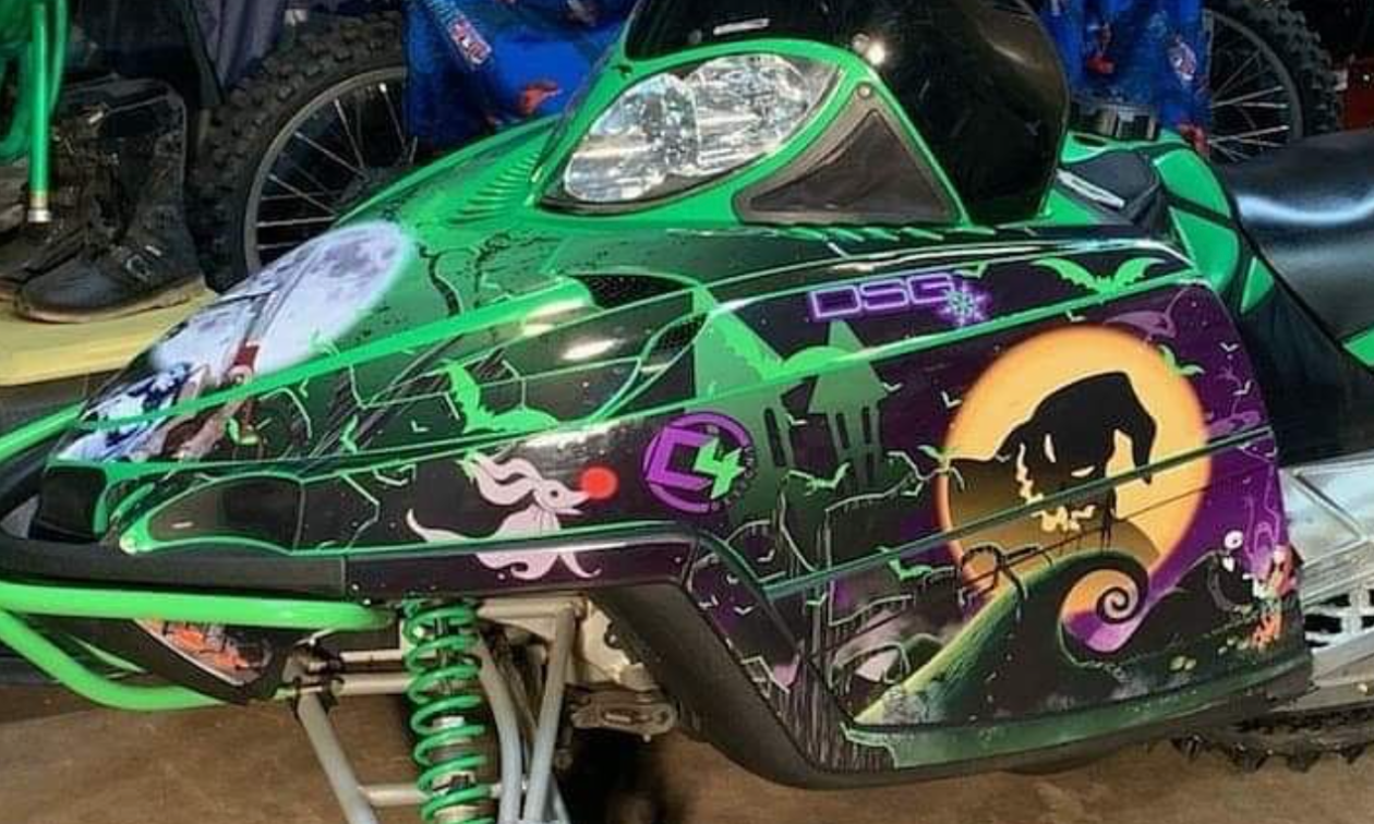 A green and black snowmobile with images of The Nightmare Before Christmas wrapped on the side. 