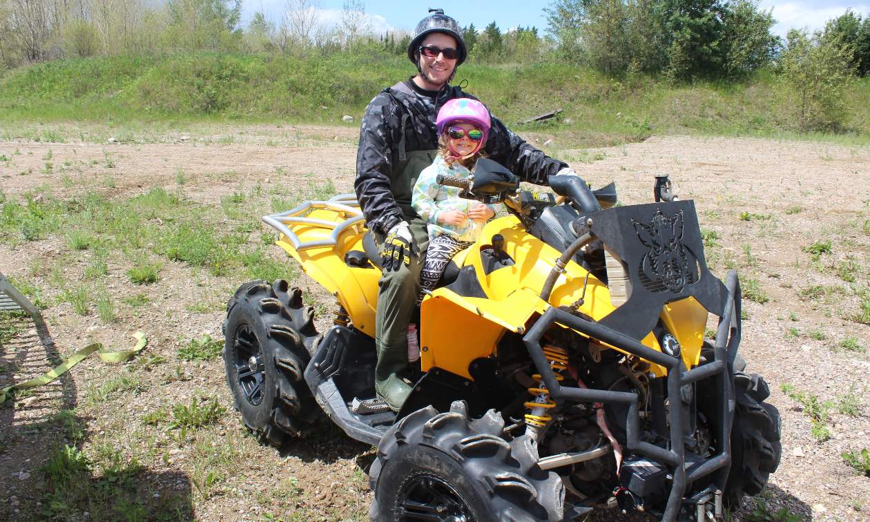 Dan Militere takes his daughter Tess for a ride on a yellow Can-Am ATV. 