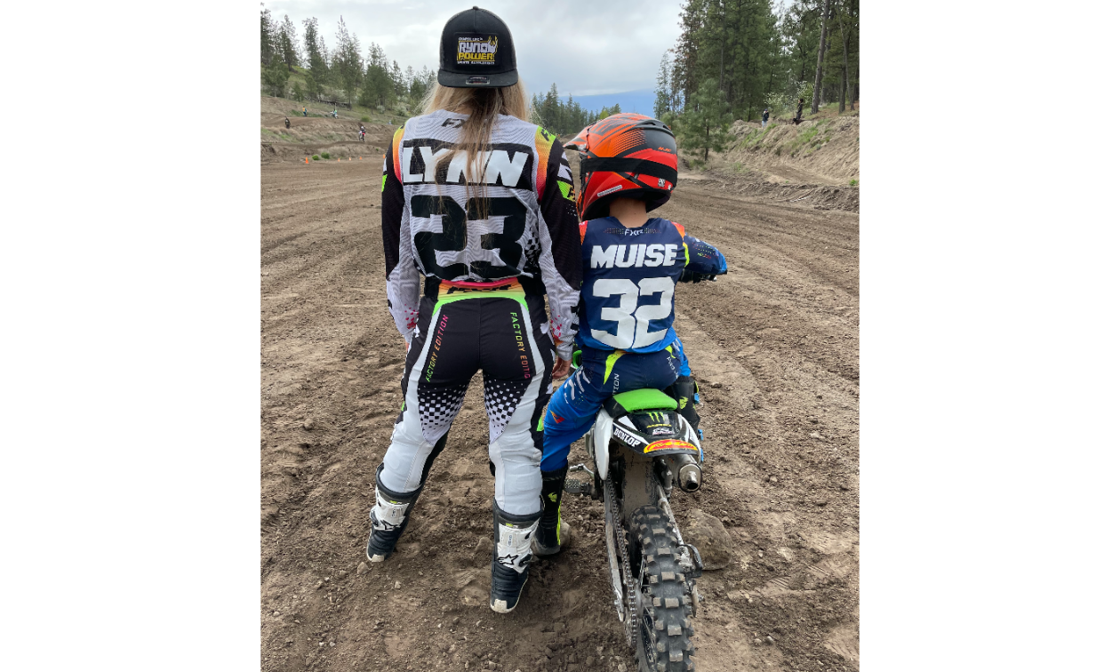 Sammi Lynn Clayton stands next to her son, Davian, as he sits on a dirt bike on a track. 