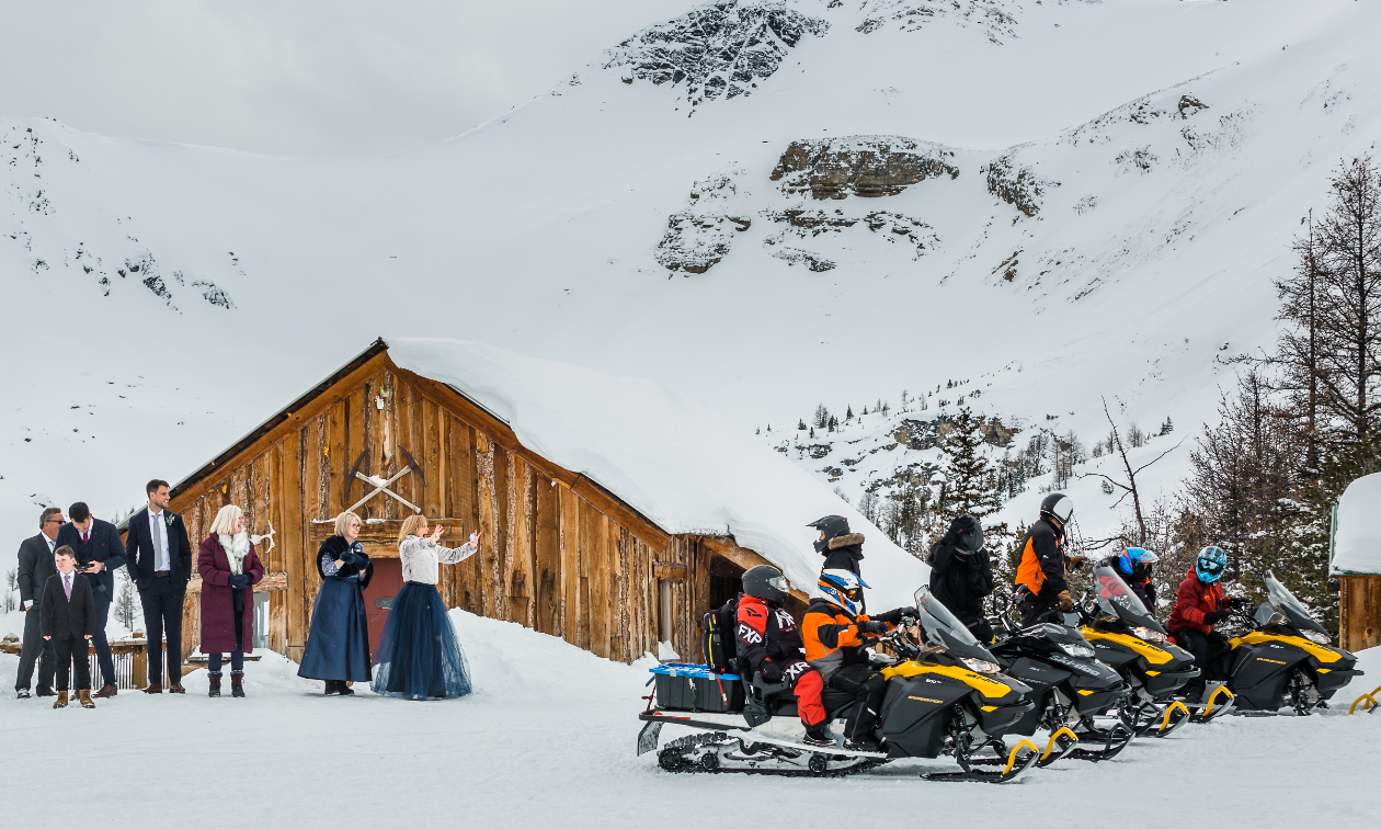 Wedding guests wave goodbye to the wedding party as they take off on snowmobiles from Toby Creek Lodge. 