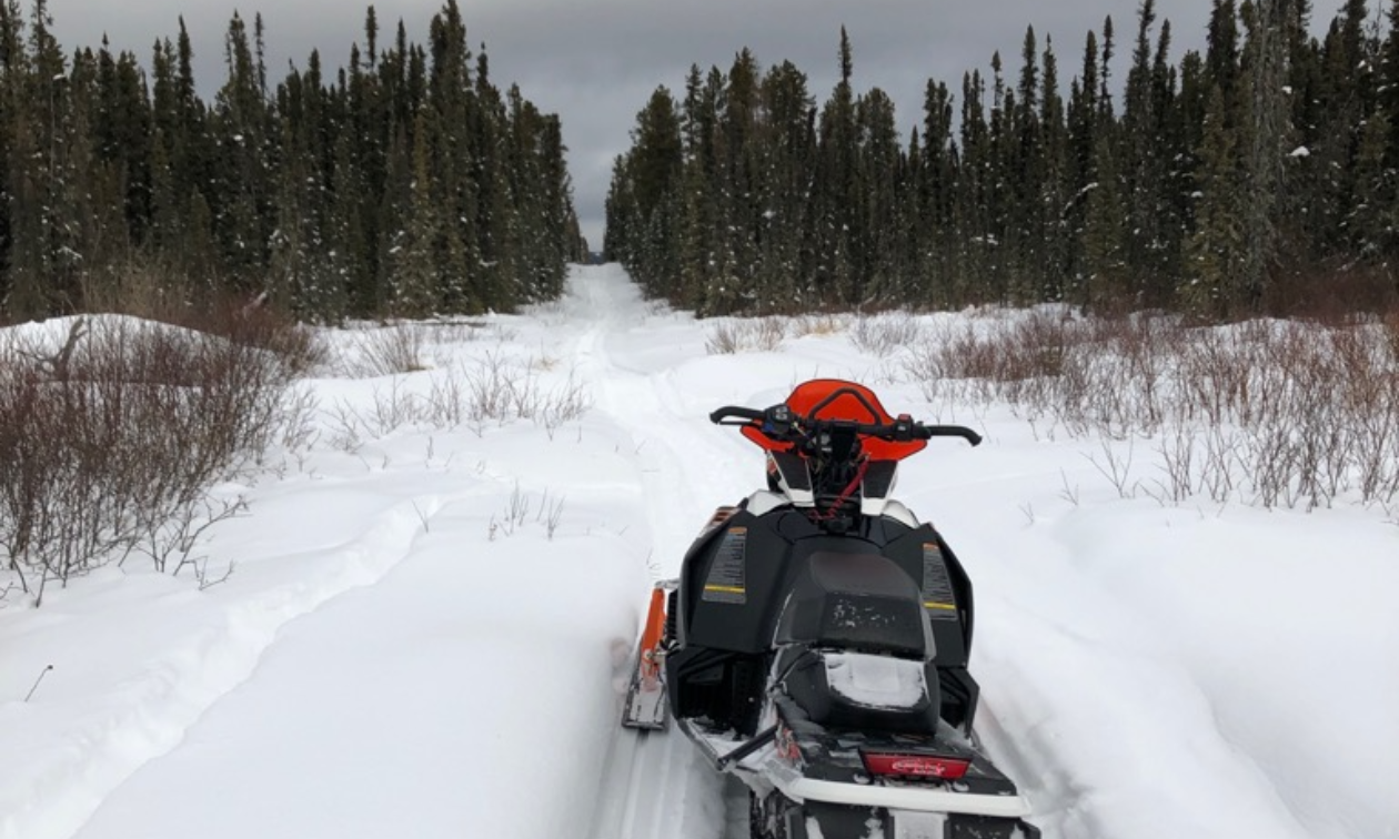 A snowmobile is parked in the snow on a trail in Swan Hills, Alberta.