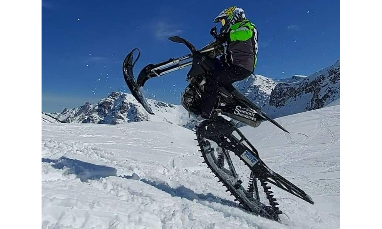 A snow biker does a wheelie on its track. 