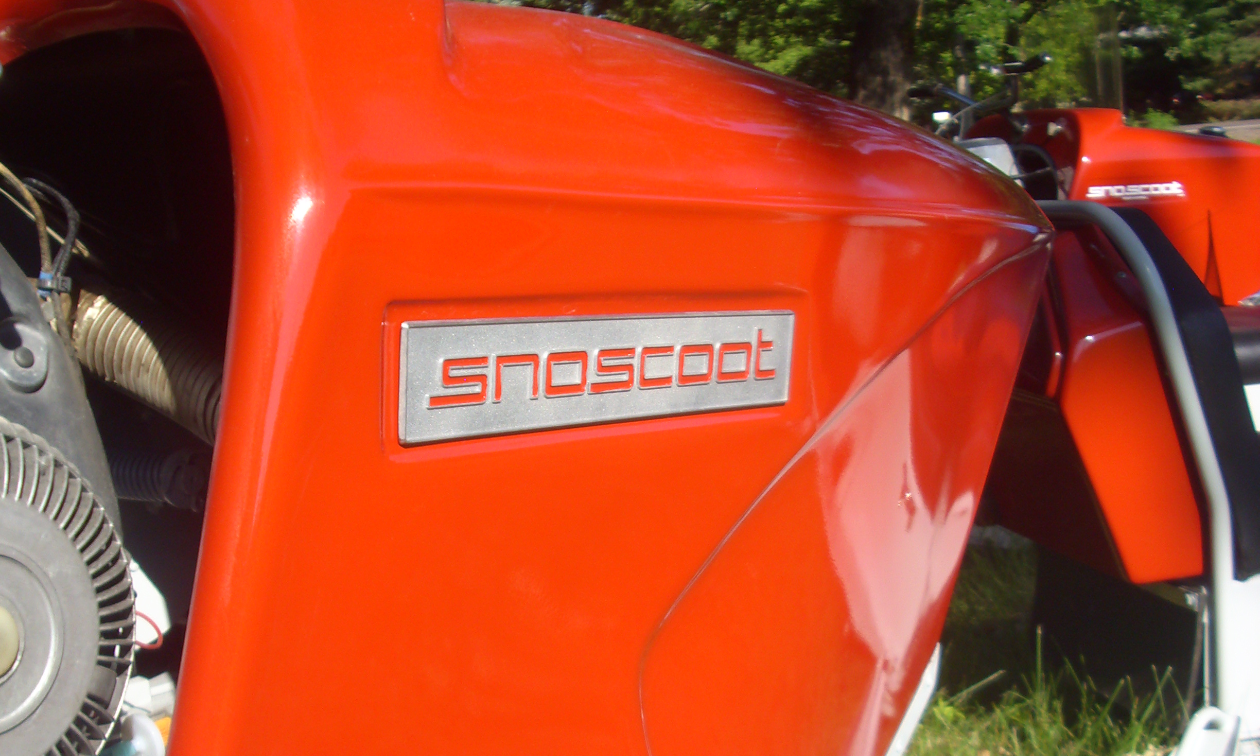 Sno Scoot is written in red on the side of a red snowmobile.