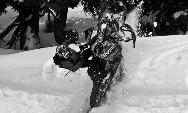 A black and white photo of a guy hitting a wind lip on a sled. 