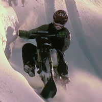 A man riding a snow bike across a steep sidehill.