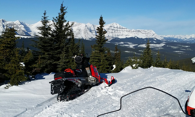 A snowmobile sitting on an overlook of the Great Divide. 