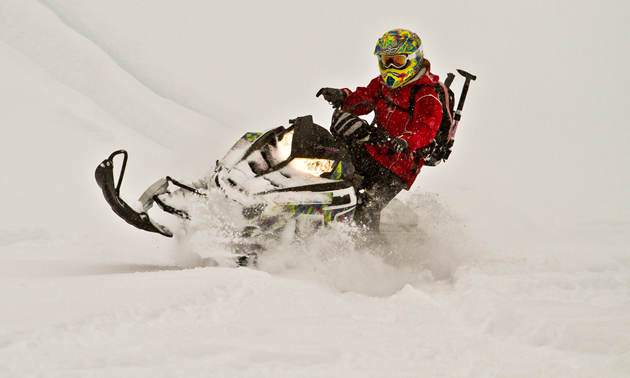 A woman in red jacket on a black snowmobile. 