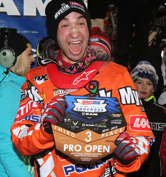 Kyle Pallin snocross racer with a big smile on his face holding a trophy. 