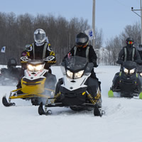 A group of women on snowmobiles out on the prairie. 