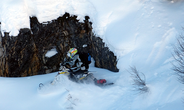 A man sidehilling across a steep section on a Timbersled snow bike. 