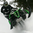 A man in black on a green snowmobile. 