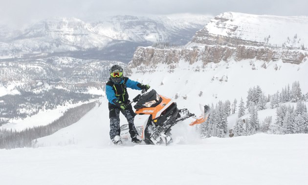 Bret Rasmussen dangling a leg off his snowmobile. 