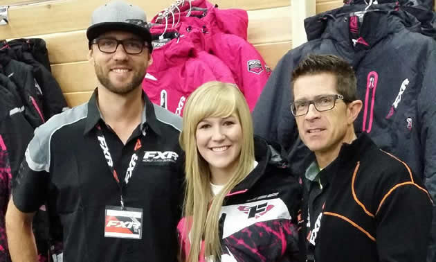 A blonde haired woman with two guys from FXR standing beside.