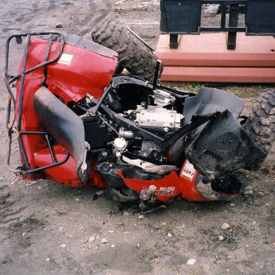 A red ATV lies in a crumpled heap next to a railway track.