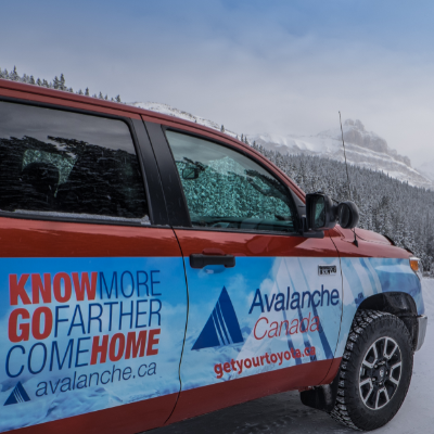 A red, white and blue truck with Avalanche Canada written on the side, parked in the mountains. 
