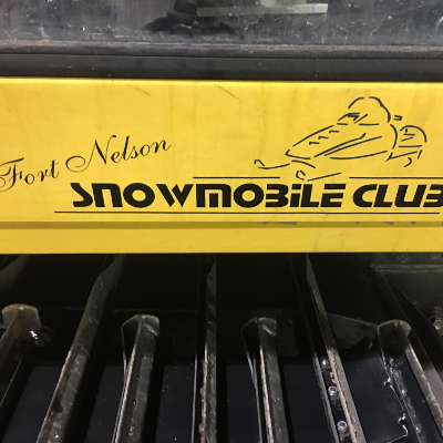 A yellow sign of the Fort Nelson Snowmobile Club
