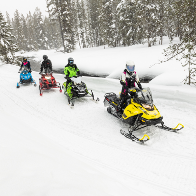 Snowmobilers ride in a line. 