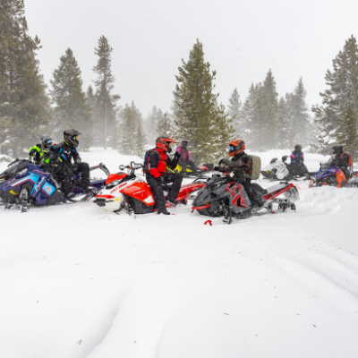 A group of snowmobiles congregate to take a break and visit. 