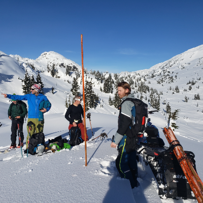 Ryan Thorley and others stand near an orange bamboo pole on a snow-covered mountain.