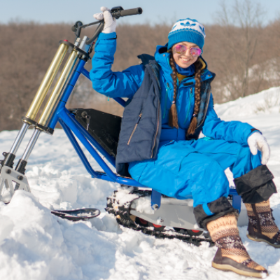 A woman sits on an electric snow scooter. 