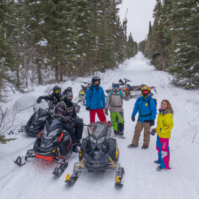 A group of snowmobilers take a break on a trail.