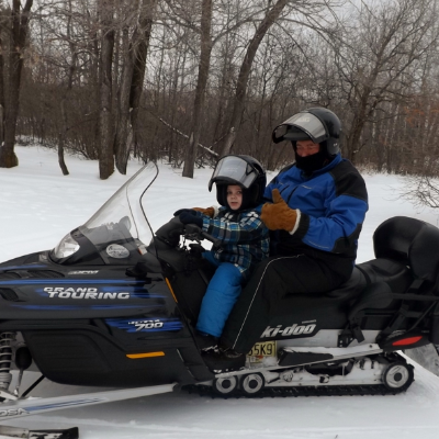 Barry Malcolm takes his grandson, Grayson, out for rides on his snowmobile.