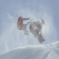 A guy hitting a cornice on his sled. 