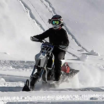 A woman riding a Timbersled snow bike. 