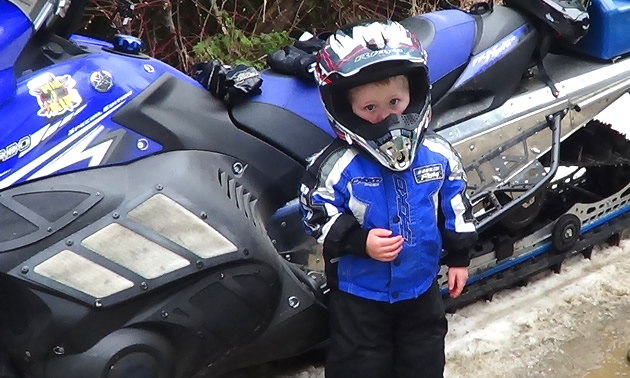 A young boy in a snowmobile suit. 