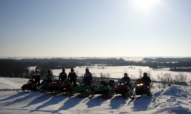 A group of sledders lined up on top of an overlook. 