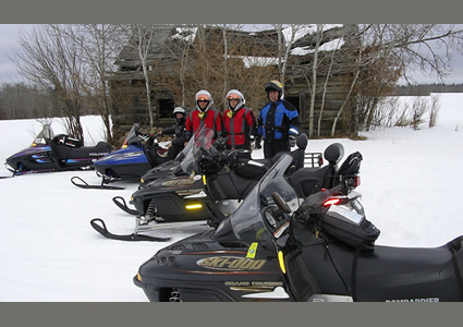 People standing outside with their snowmobiles.