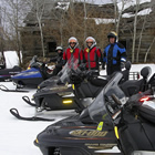 People standing outside with their snowmobiles.