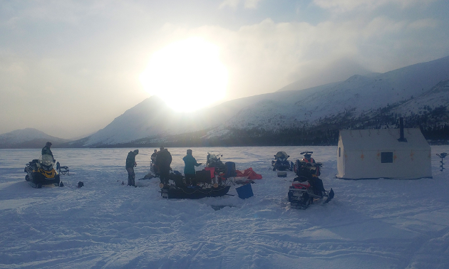 Snowmobilers gather around a warm-up shelter next to Alligator Lake.