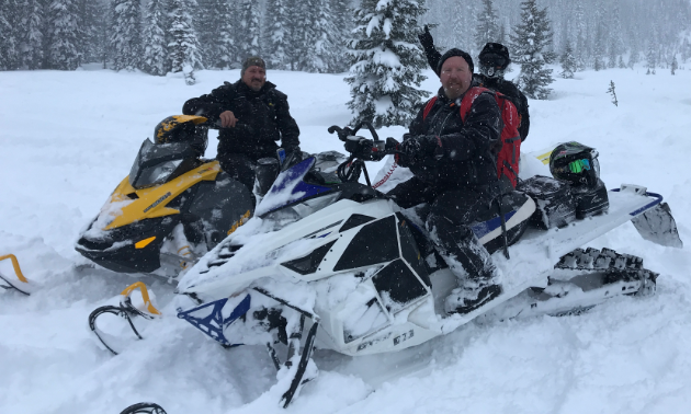 Three snowmobilers smile for the photo.